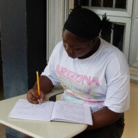 Young Jermelia sits on the corridor of UTech, Jamaica completing her Math Work.